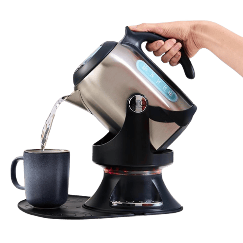 A hand tilting the Gilia kettle on its pivot base to pour water into a mug